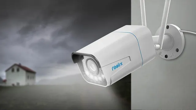 KAAMERAMAAILM.EE - Valvekaamera Reolink RLC-511WA 5MP Dual Band WiFi 5-kordse suumiga on paigaldatud välisseinale, jälgides õueala, mille taustal on näha hägune maja ja pilvine taevas, mis viitab akti | kaameramaailm.ee KAAMERAMAAILM.EE - Valvekaamera Reolink RLC-511WA 5MP Dual Band WiFi 5-kordse suumiga on paigaldatud välisseinale, jälgides õueala, mille taustal on näha hägune maja ja pilvine taevas, mis viitab akti